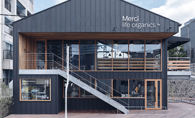 Merci life organicsの店舗外観（正面）。黒い外壁と木目調のアクセントが印象的な2階建ての建物